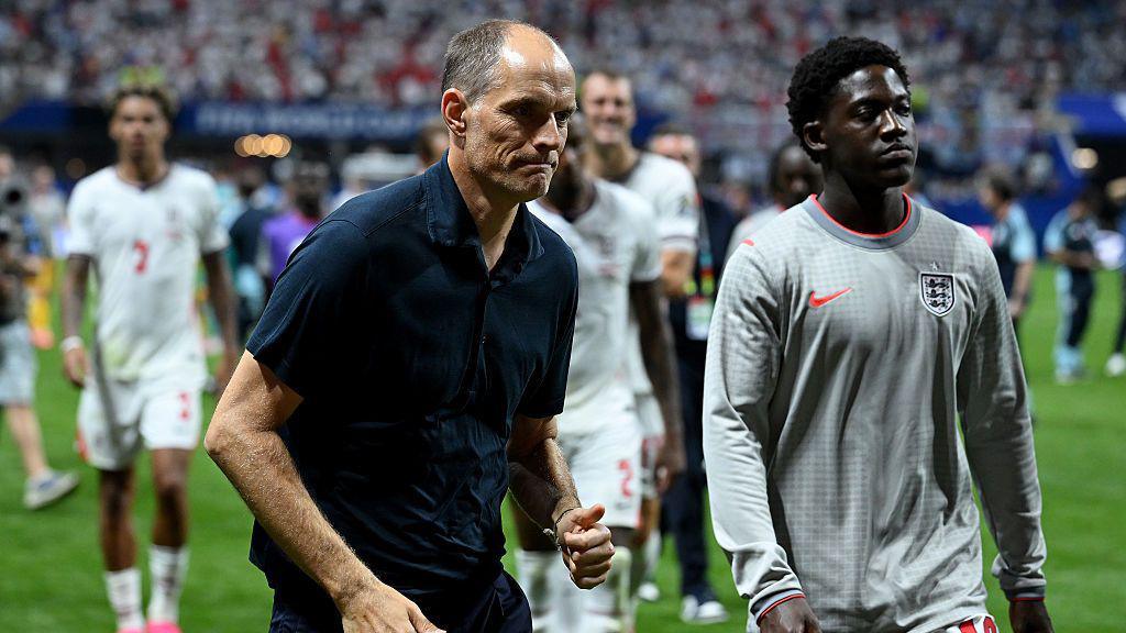 Thomas Tuchel walks off the pitch with Kobbie Mainoo