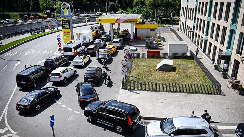 People queue to refuel their cars at a Rosneft gas station in Moscow