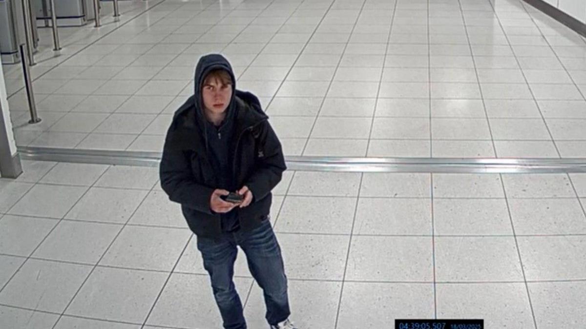 A CCTV image of a teenage boy wearing jeans and a hoodie at Manchester Airport