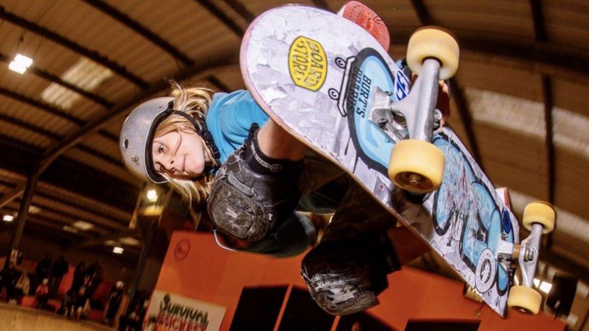 Jaxon Popovic holds a skateboard in mid-air