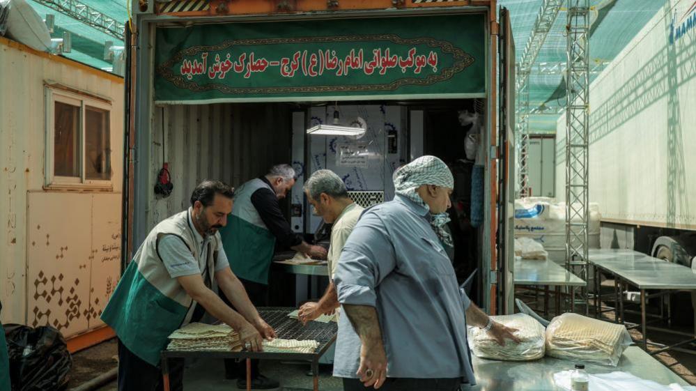 Four men preparing bread in a cooling area