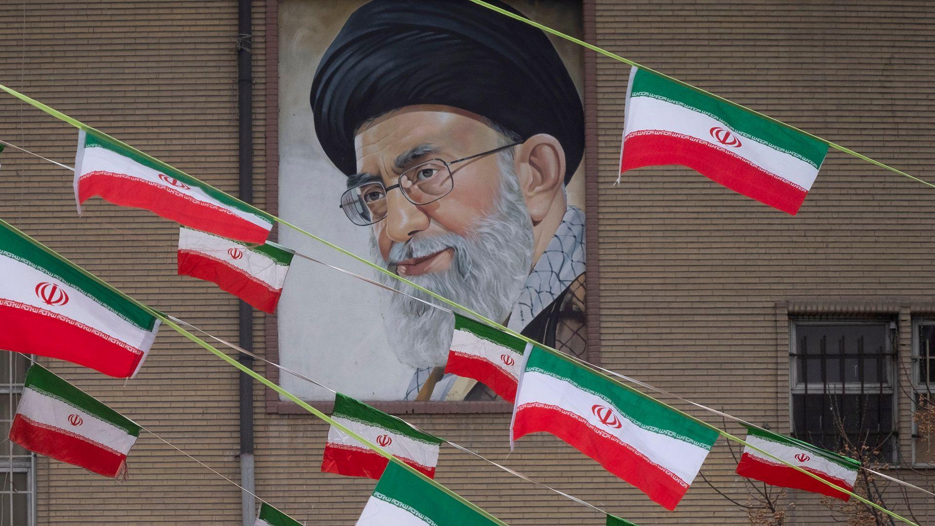 A mural of Iran's Supreme Leader Ayatollah Ali Khamenei is seen on the side of a building in Azadi avenue with reams of Iranian national flags hanging in the foreground, in Tehran on 11 February 2022.