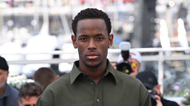 Ward looks straight at the camera at an event. He is wearing a green collared shirt and is wearing an earring.