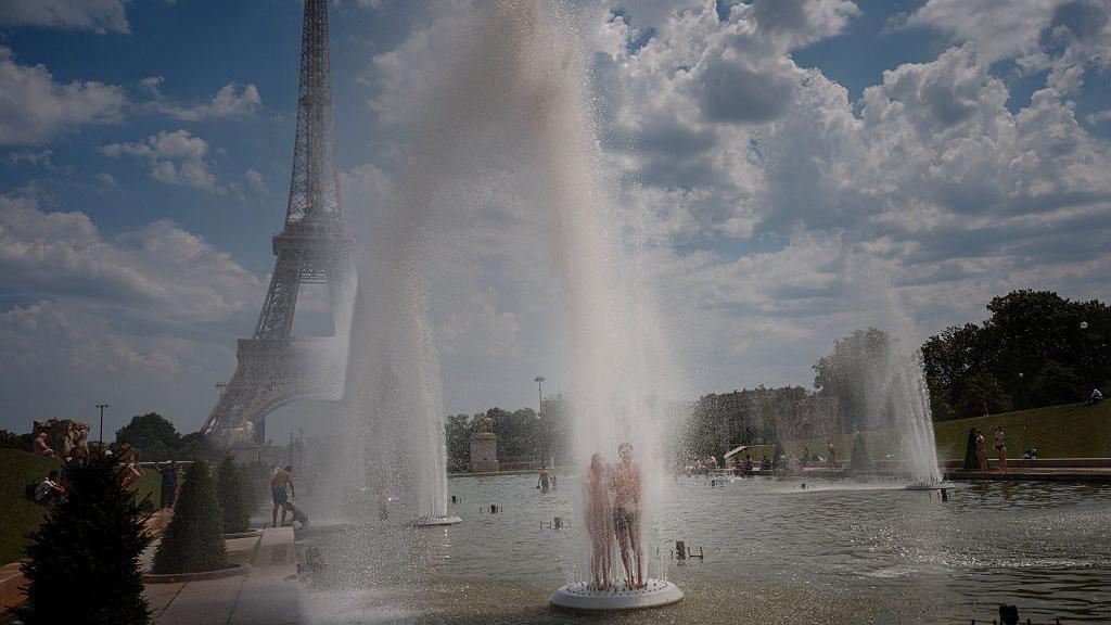A photo of people cooling off in a fountain in Paris near the iconic Eiffel Tower