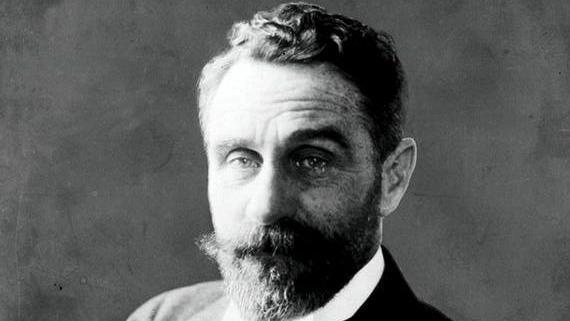 An archive image of Roger Casement in Black and white. He has a thick beard and moustache, and short wavy hair.