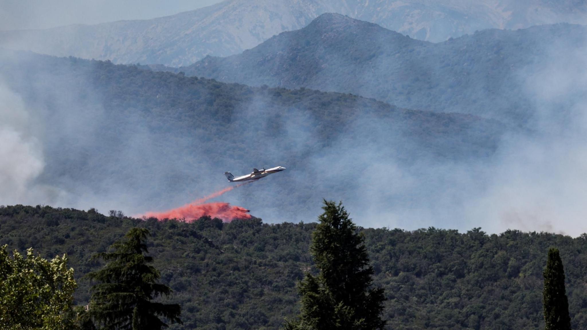 A firefighting plane drops fire retardant as it flies over a wildfire in Ille-sur-Tet near Perpignan in southern France.