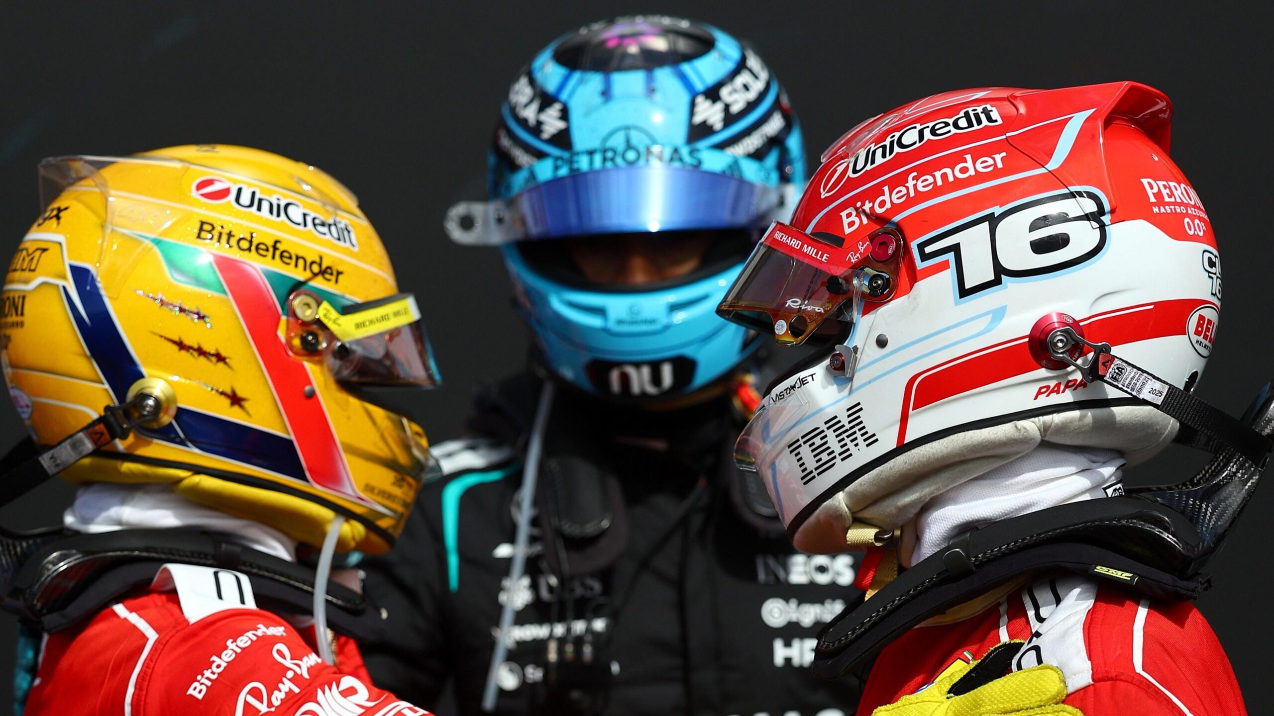 Race winner Ferrari's Charles Leclerc hugging team-mate Lewis Hamilton and second place George Russell watches the pair behind them