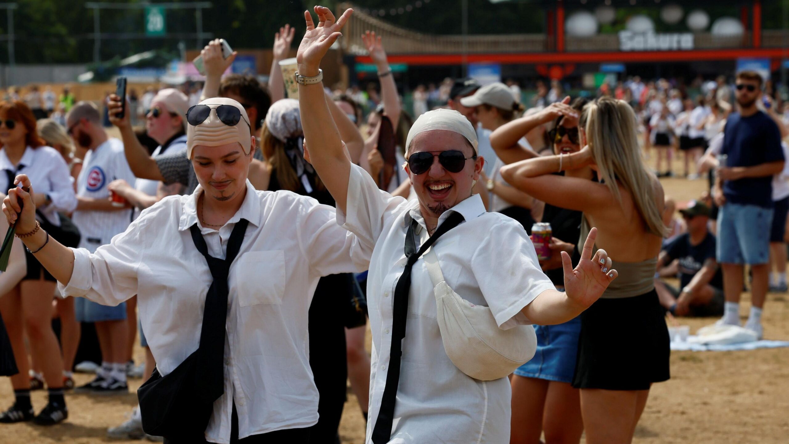 Fans dressed as Pitbull in white shirts and bald caps dance in the crowd.