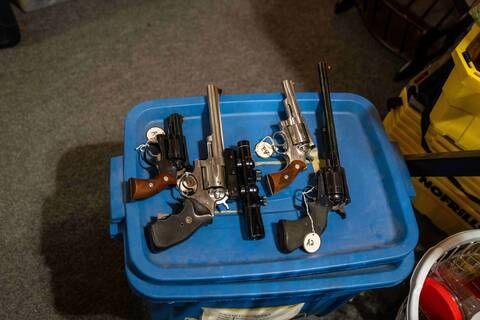 Small firearms are laid on a blue container and tagged in a Dauphin, Manitoba home.