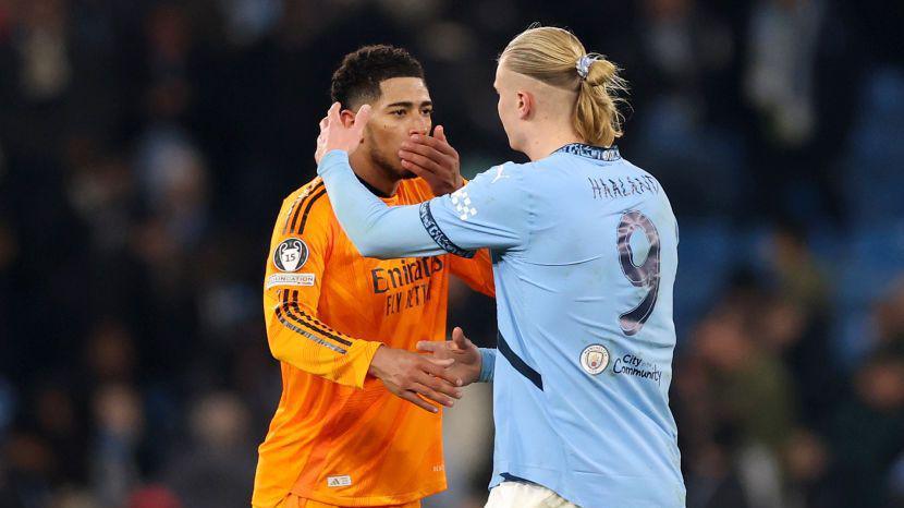 Jude Bellingham covers his mouth talking to Erling Haaland who is about to hug him