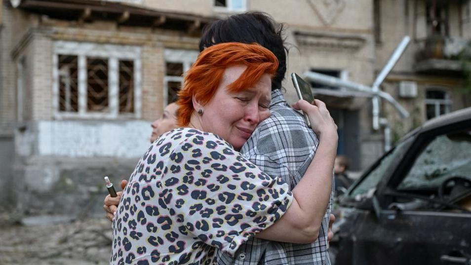 An upset woman hugs another person