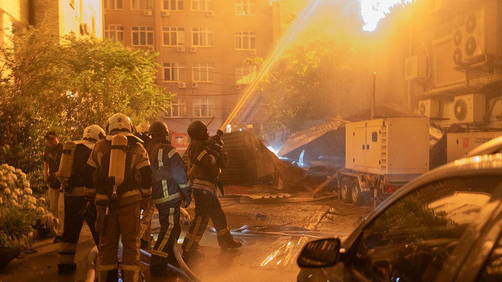 An explosion is seen after a Russian drone strikes a building as Ukrainian firefighters battle a fire in another building previously hit by a drone during a Russian air attack on Kyiv.