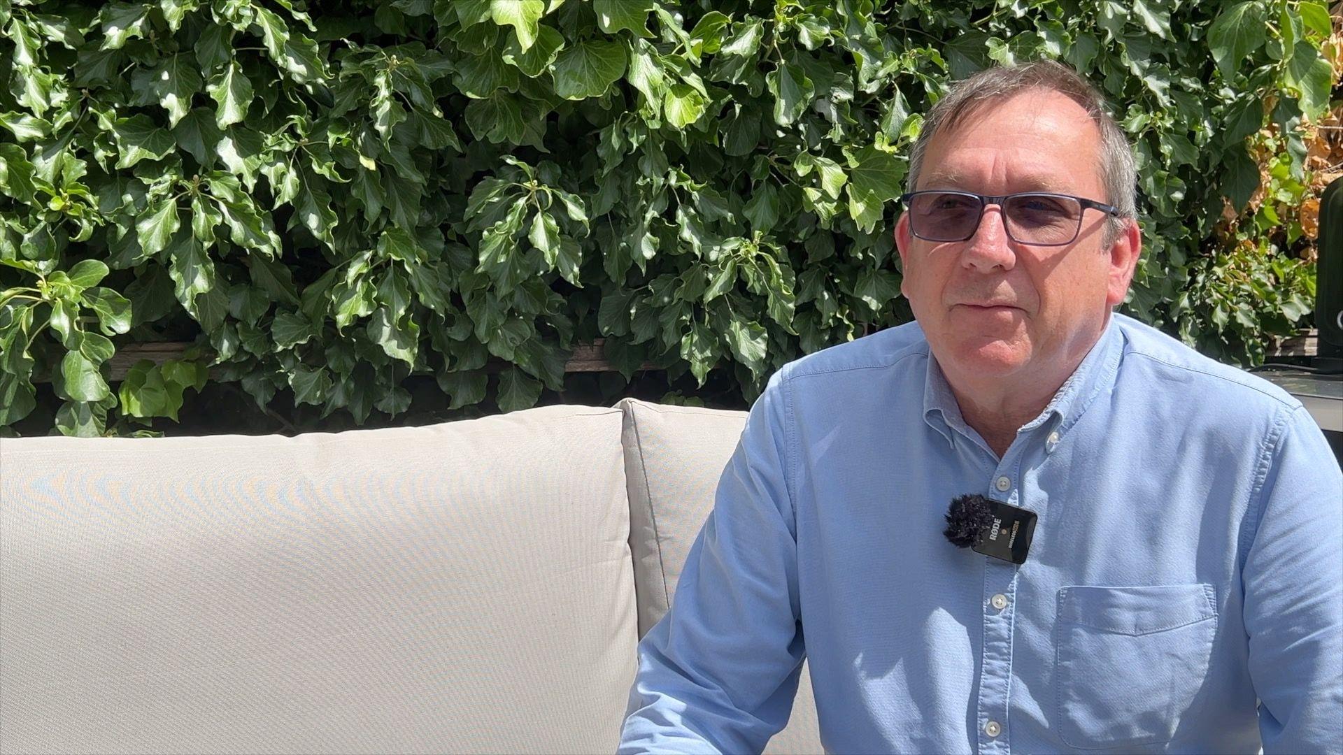 Russell Barton sitting on outdoor furniture in his garden.