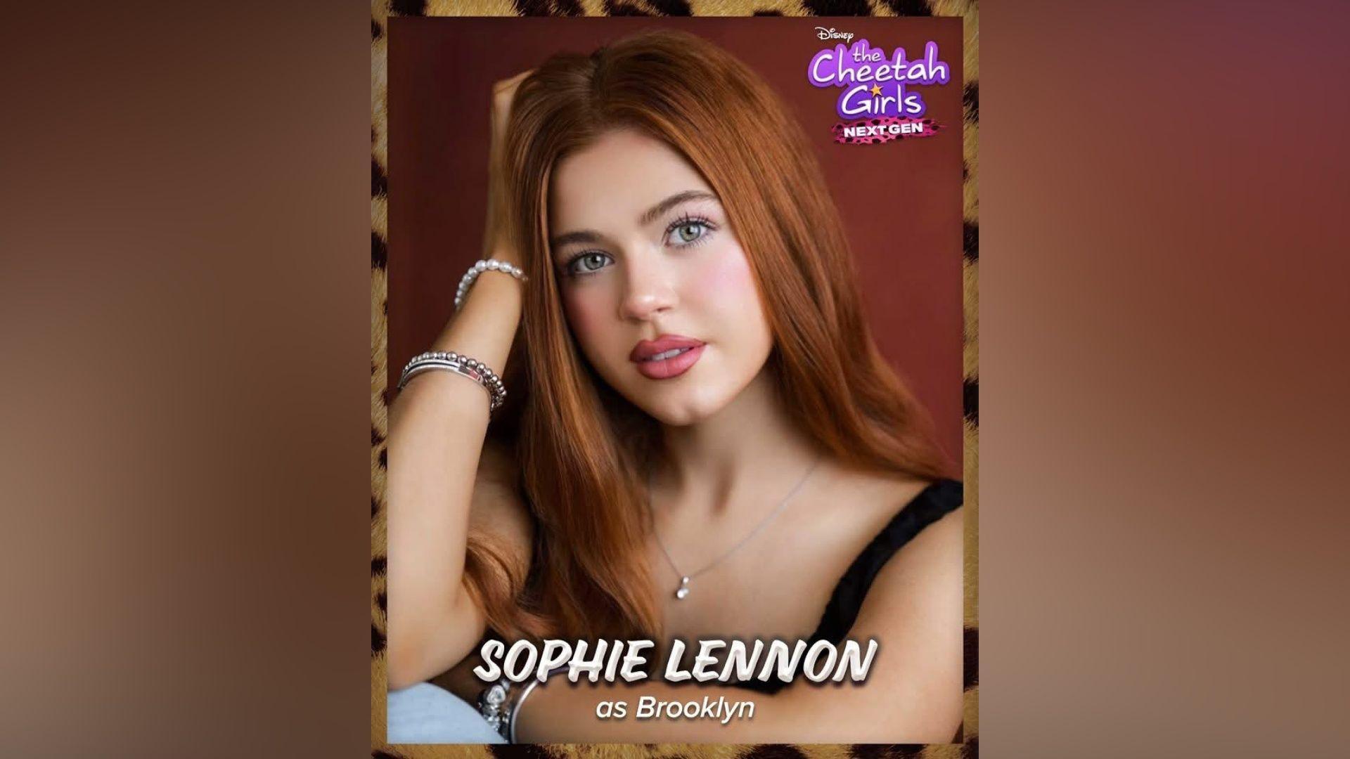 A teenage girl with long ginger hair. She is wearing pink lipstick and a black vest top. In the top right corner there is purple text that reads "The Cheetah Girls next gen".
