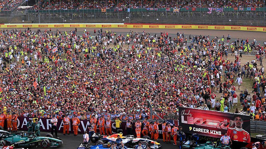 Fans run out on the Silverstone track after the race to watch Charles Leclerc, George Russell and Lewis Hamilton lift their trophies at the British Grand Prix