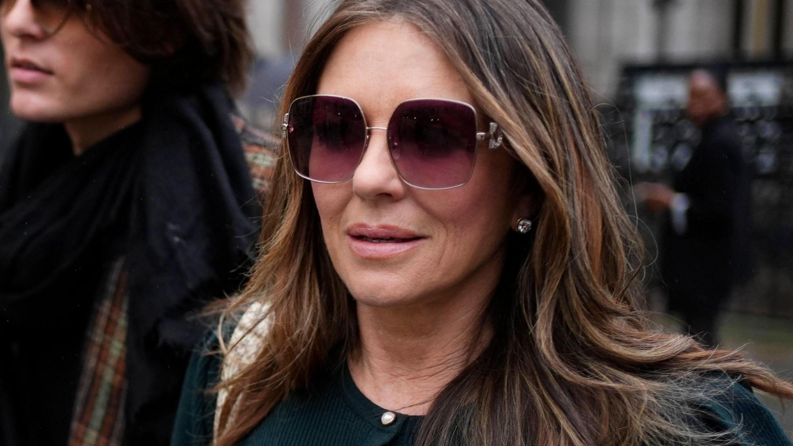 Elizabeth Hurley, in a green outfit and sunglasses, leaves the Royal Courts of Justice