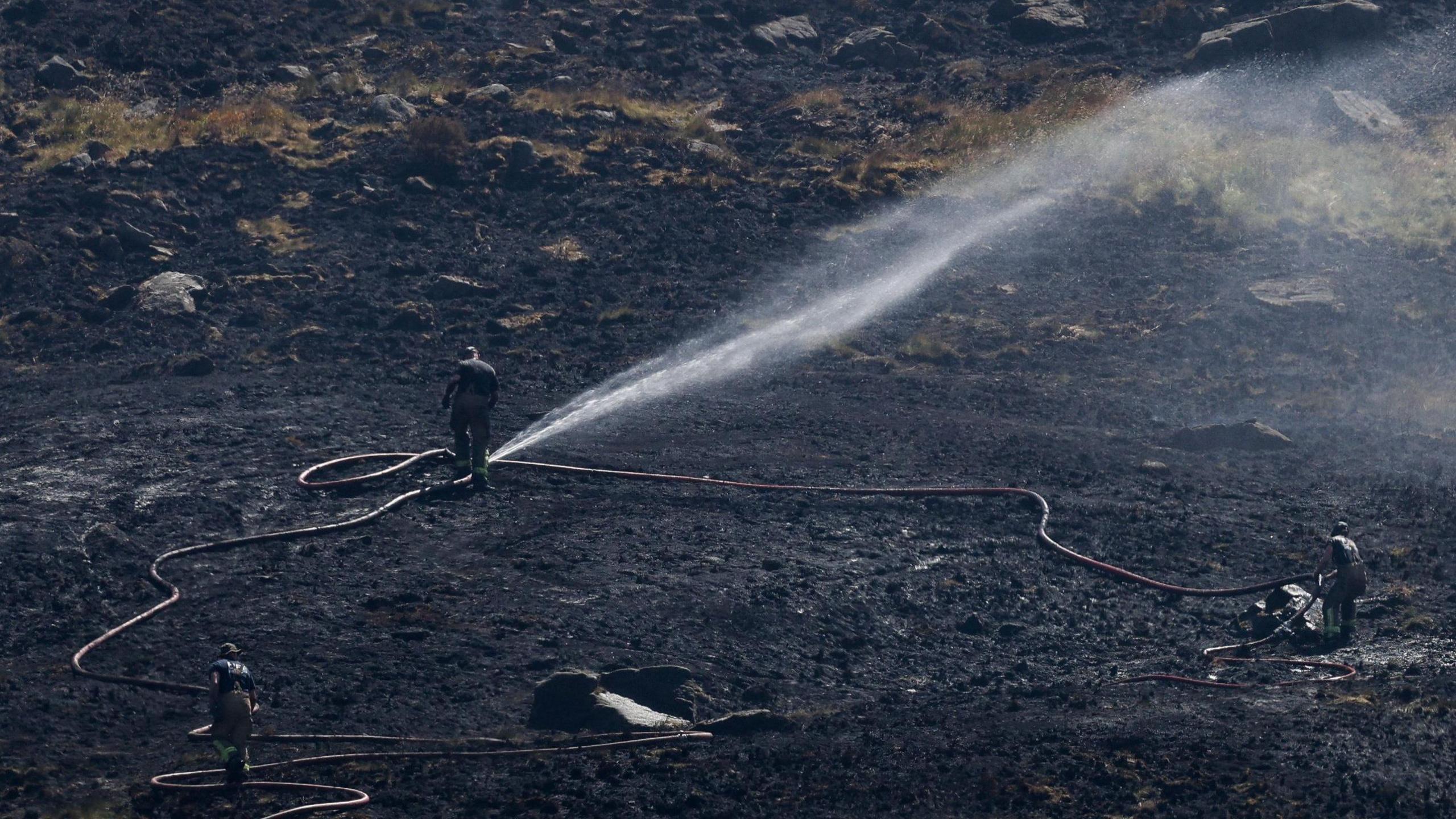 Firefighter on Dove Stone spraying jets of water over the moorland.