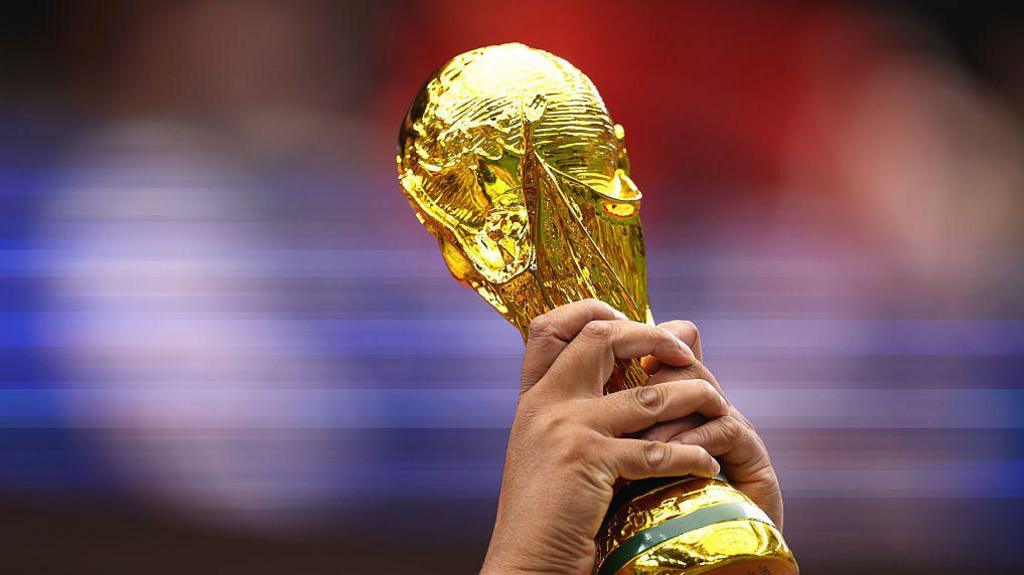 Close-up of a man's hands holding up a replica World Cup trophy at the 2026 match between Canada and Morocco in  Houston, Texas