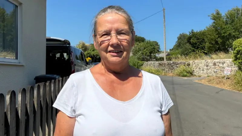 Jane Parsons is seen in a white T-shirt looking toward the camera.