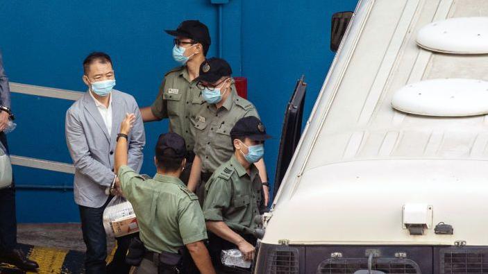 Wu Chi-wai, a former pro-democracy lawmaker, walk towards a Correctional Services Department (CSD) vehicle