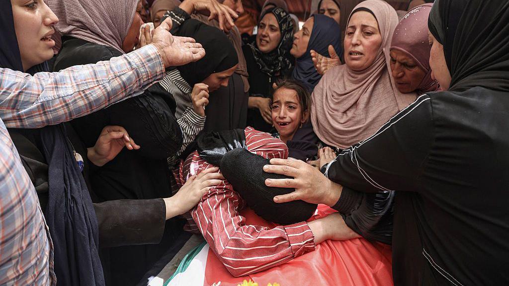 Relatives mourn over the body of 17-year-old Palestinian Fadi al-Nassan during his funeral in the village of al-Mughayyir, in the occupied West Bank (18 July 2026)