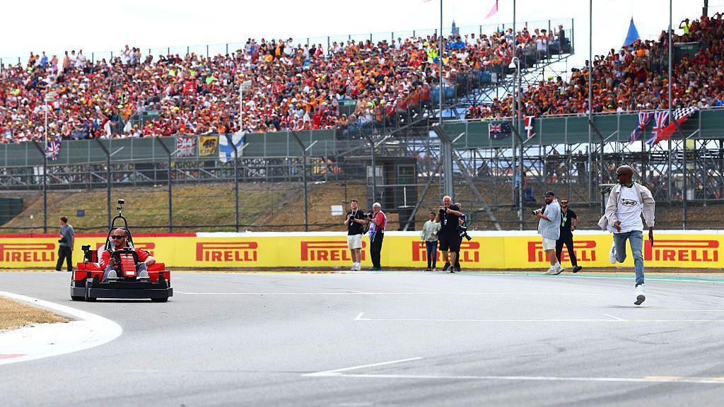 Mo Farah runs alongside Lewis Hamilton's lego kart during the mini lego race at the British grand prix, ahead of the race on Sunday