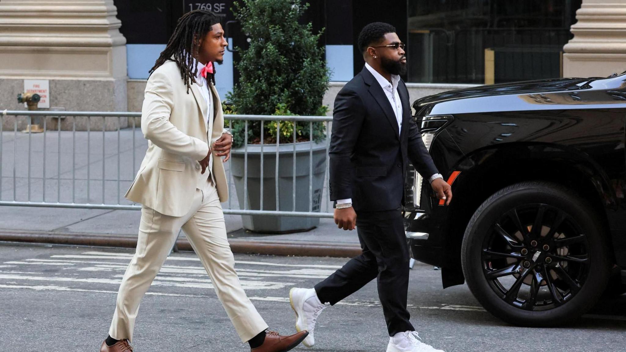 NFL athlete Isiah Pacheco arrives at Madison Square Garden wearing a cream suit and tan shoes.
