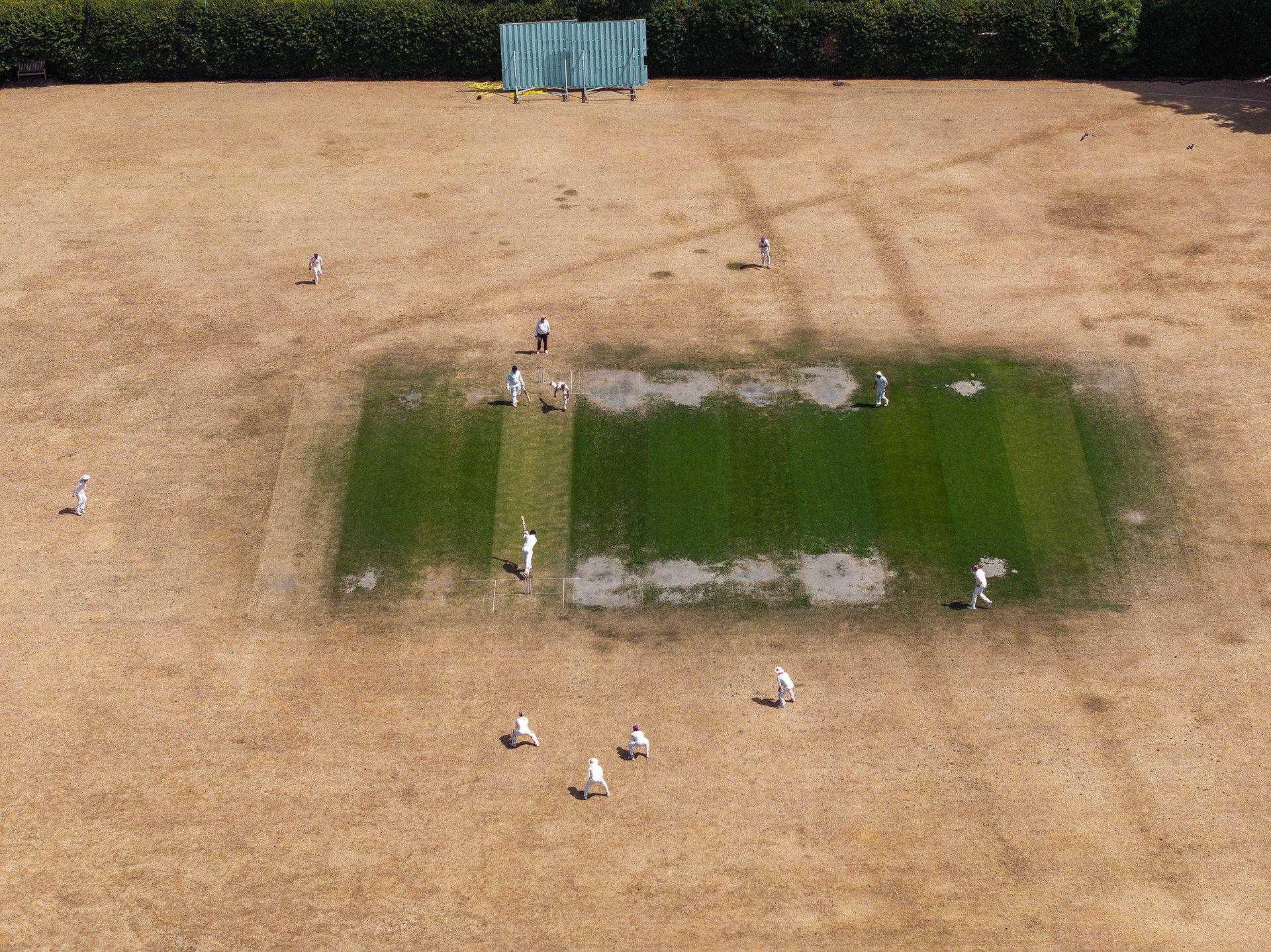 In this aerial view the Maidenhead & Bray CC 1st XI take on the Boyne Hill CC 1st XI on a bone dry field at the Maidenhead & Bray County Cricket club on July 25, 2026 in Bray, United Kingdom.