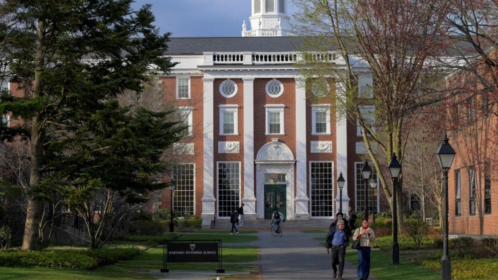 People walk in front of a Harvard Business School building