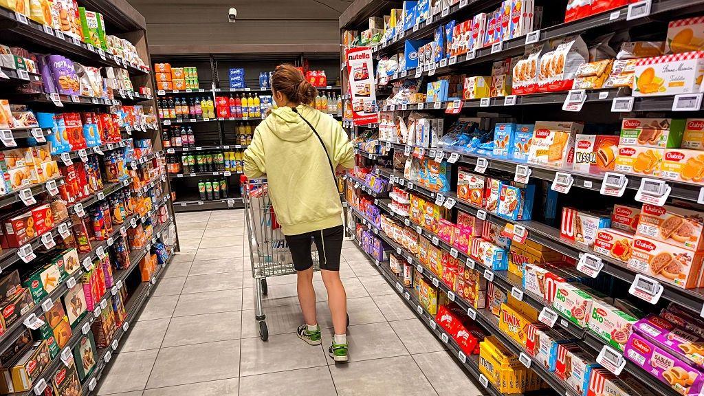 A woman shops pushes her shopping cart through a cake and biscuit aisle at an Intermarché  supermarket in France.