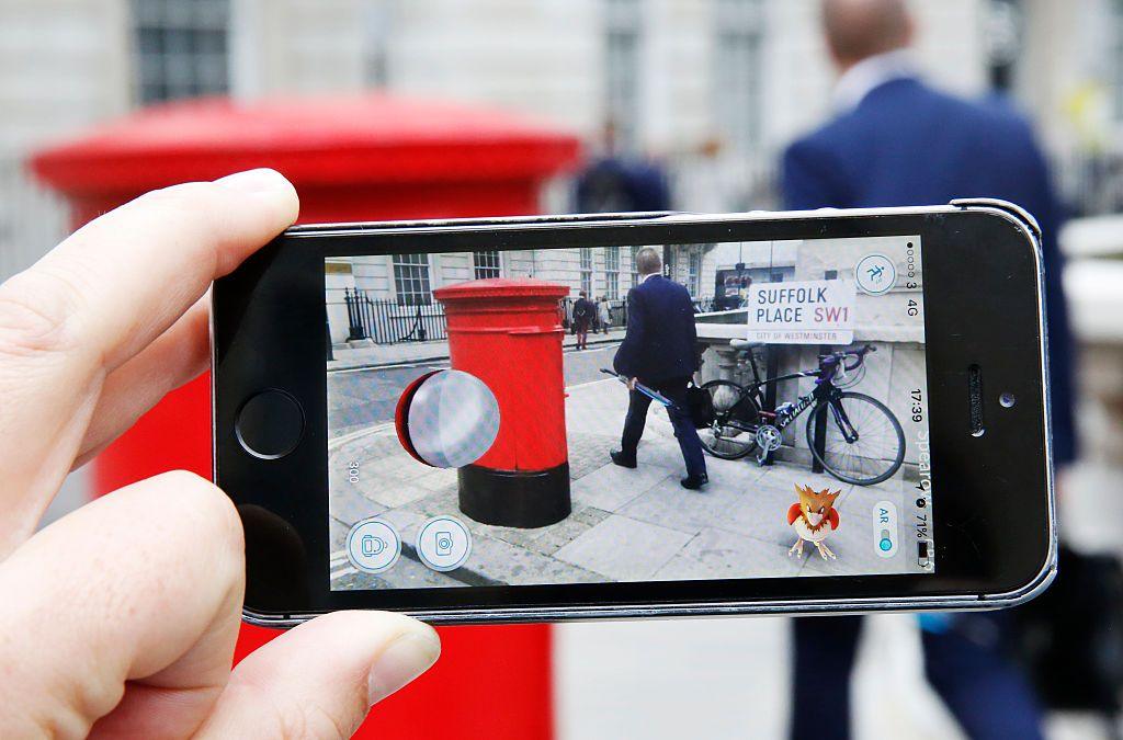 A phone held horizontal with the Pokémon Go game running over a UK address of Suffolk place. A Spearow sits in the corner on the phone.