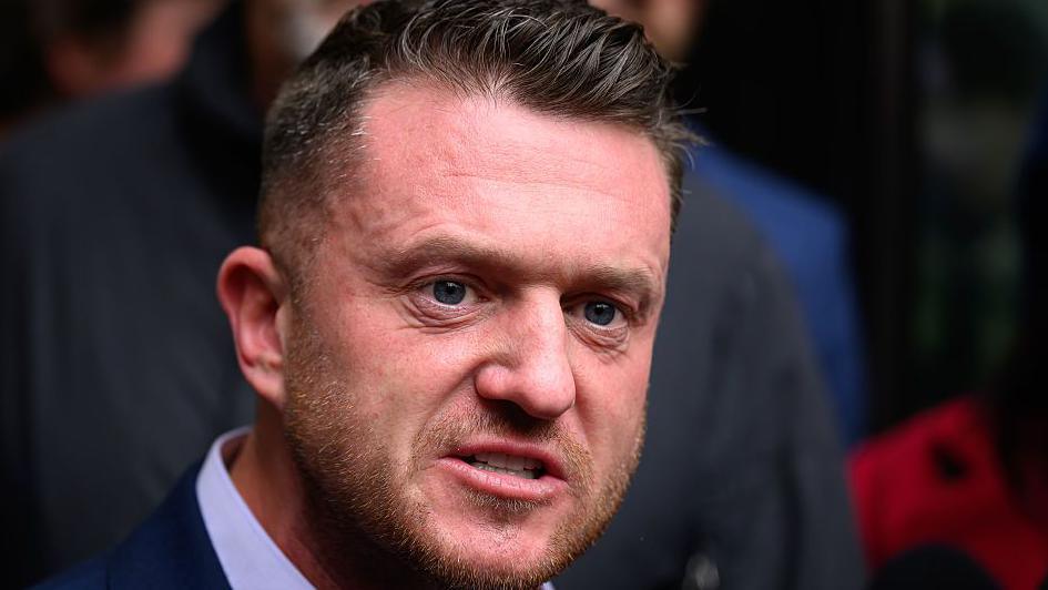 A headshot of Tommy Robinson - a white man with short hair and a light coloured beard.