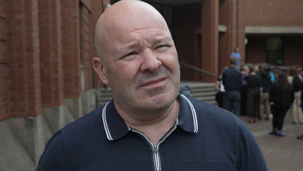 Nigel Hotham standing outside Hull Crown Court. He has a shaven head and is wearing a blue and white polo shirt.