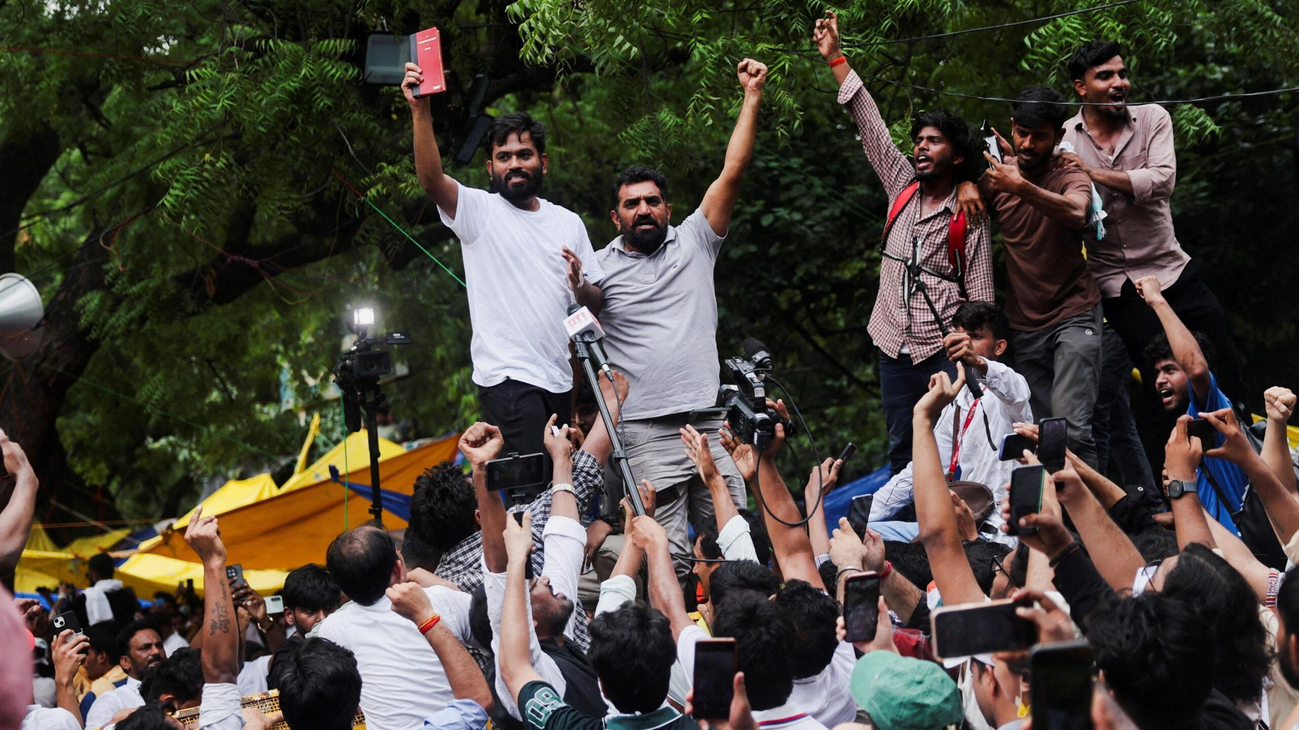 Abhijeet Dipke, head of the Cockroach Janta Party (CJP), celebrates with supporters who stand on an elevated platform holding their hands up in triumph
