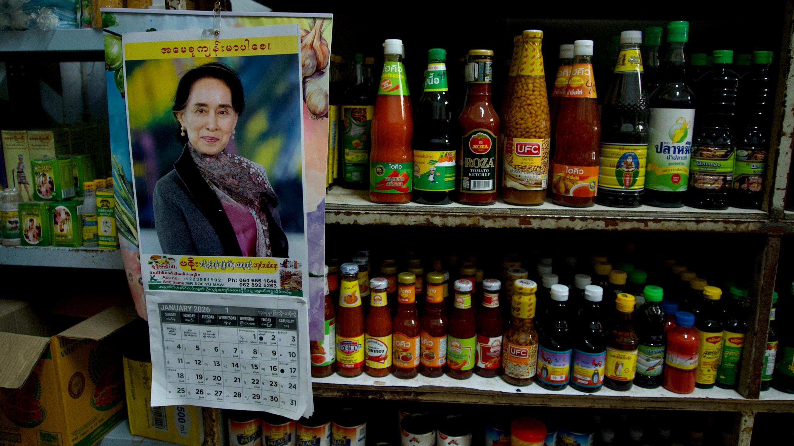 A calendar with the image of Aung San Suu Kyi hangs beside bottles of Burmese sauses and condiments in Mae Sot Thailand, which borders Myanmar