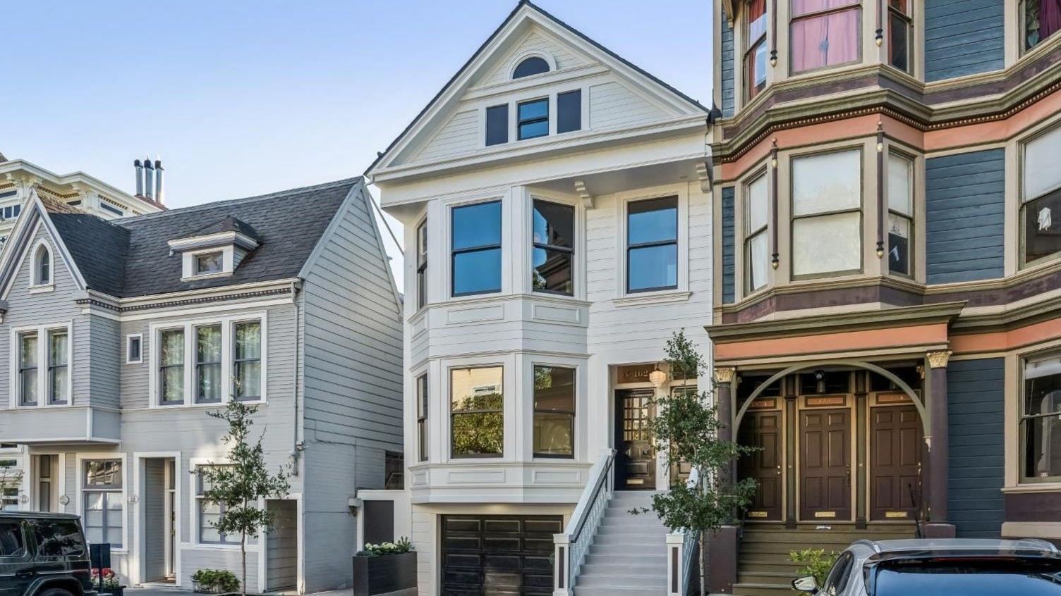 Three homes on a residential street in San Francisco. The three floor homes look clean and well maintained with well-trimmed plants and trees outside.