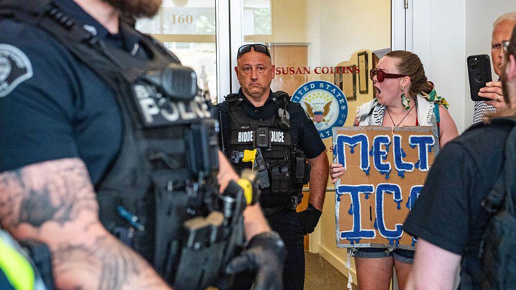 Protesters outside Susan Collins office, seen next to police.