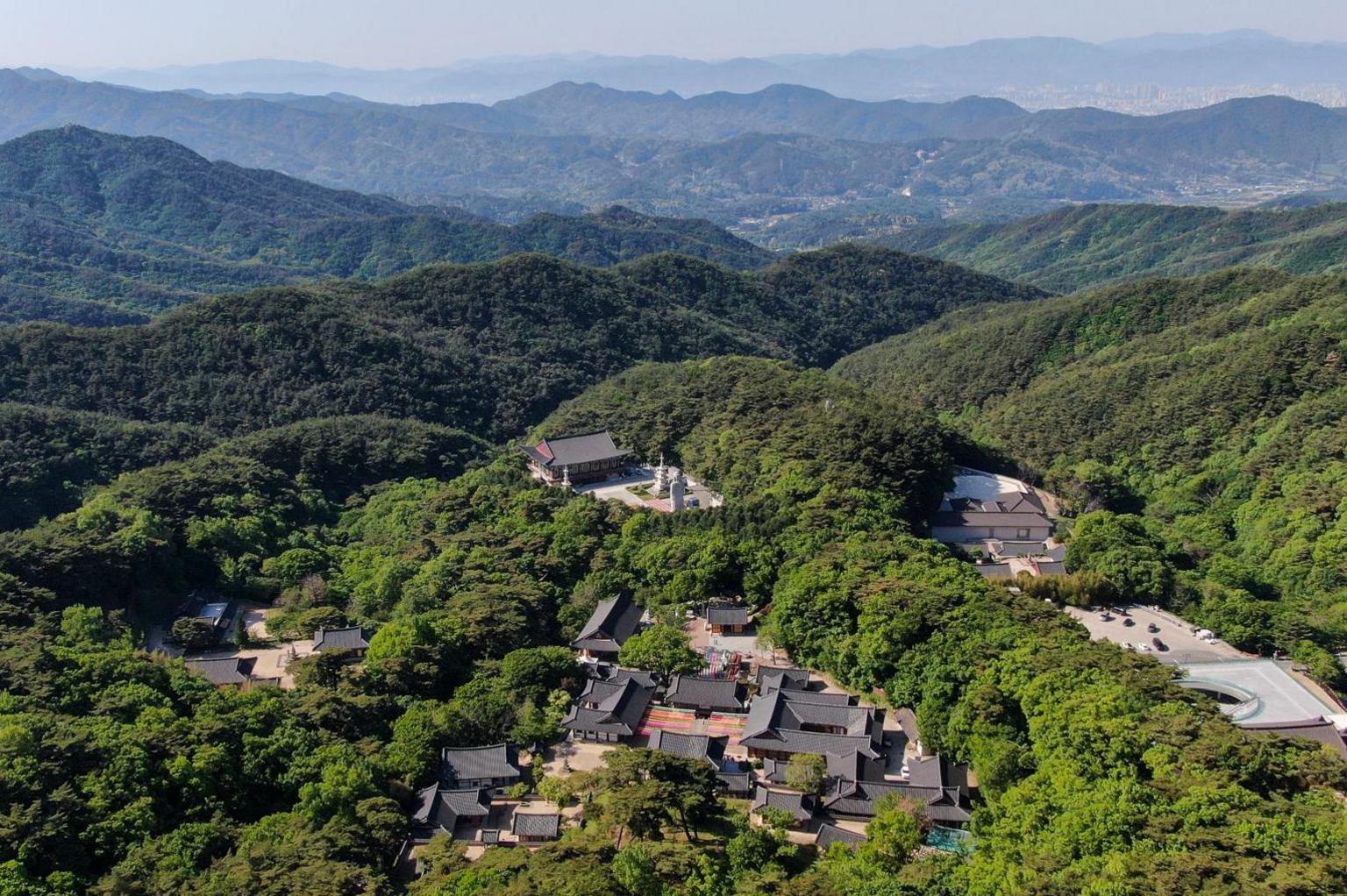 An aerial view of Donghwasa Temple, surrounded by dense woodland in the mountains near Daegu, South Korea