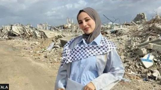 A girl in Gaza stands before a background of rubble