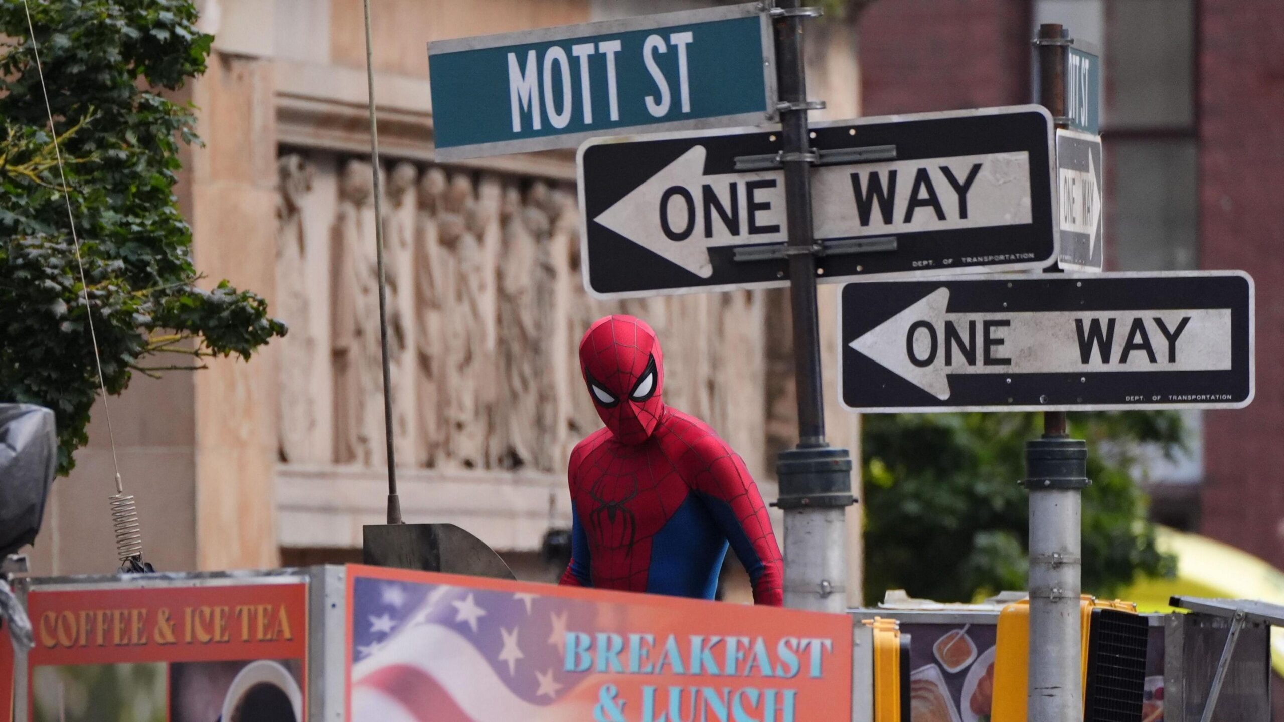 Spiderman looking at the camera with "one way" road signs behind him