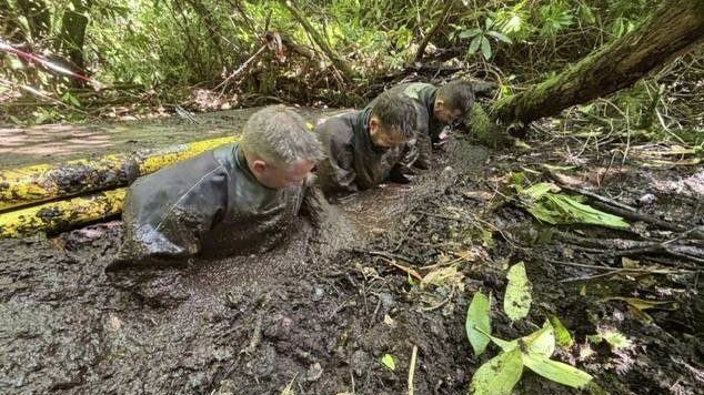Three police officers wading through mud as part of search of woodland near Desborough's cabin.