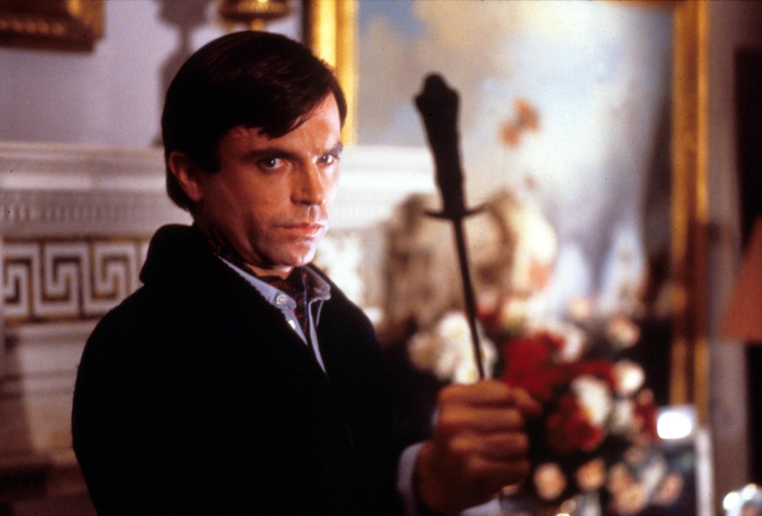 Sam Neill in The Omen holding a crucifix