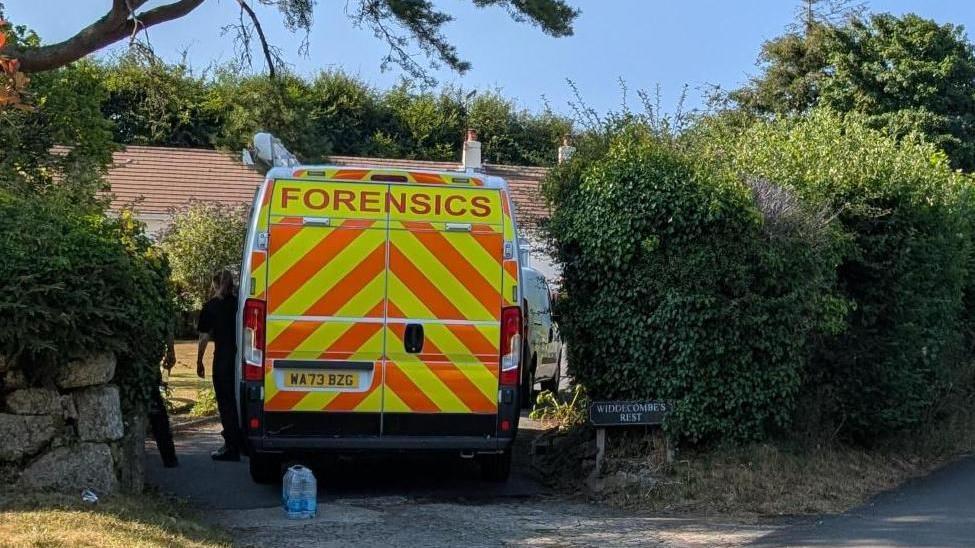 A forensics van is pictured next to a hedge at Widdecombe's home