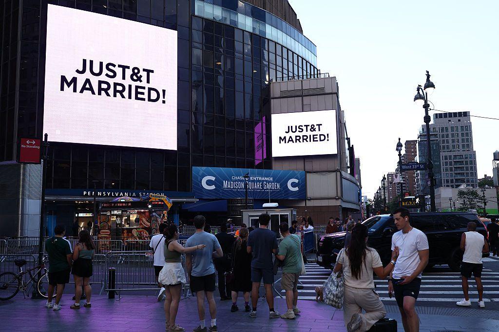 People watch giant screens showing the message "JUST&T MARRIED!" (T&T for Taylor and Travis) outside Madison Square Garden, the reported venue for the wedding celebrations of pop singer Taylor Swift and pro-athlete Travis Kelce.