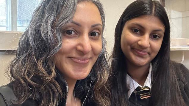 Sharan (pictured on the left) sits with her daughter Simran. Simran is 15 and is wearing her school uniform.