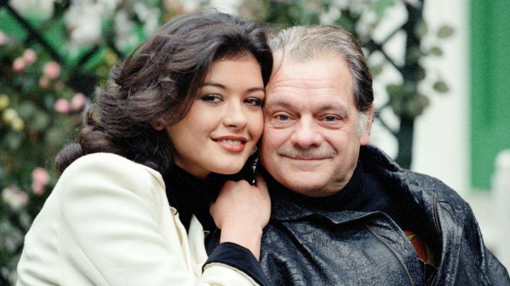 Jones with David Jason in character. Jones, on the left, wears a white jacket and has dark brown wavy hair. Jason, on right, wears a black leather jacket and has short grey hair and a moustache.