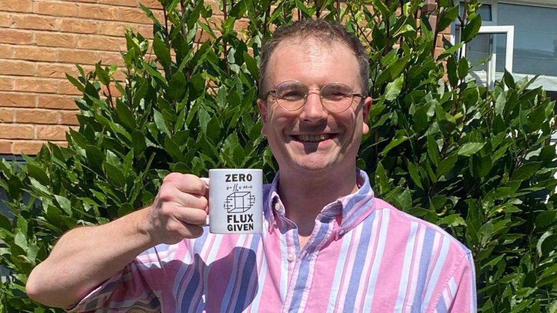 Tim holding a mug that says 'zero flux given'