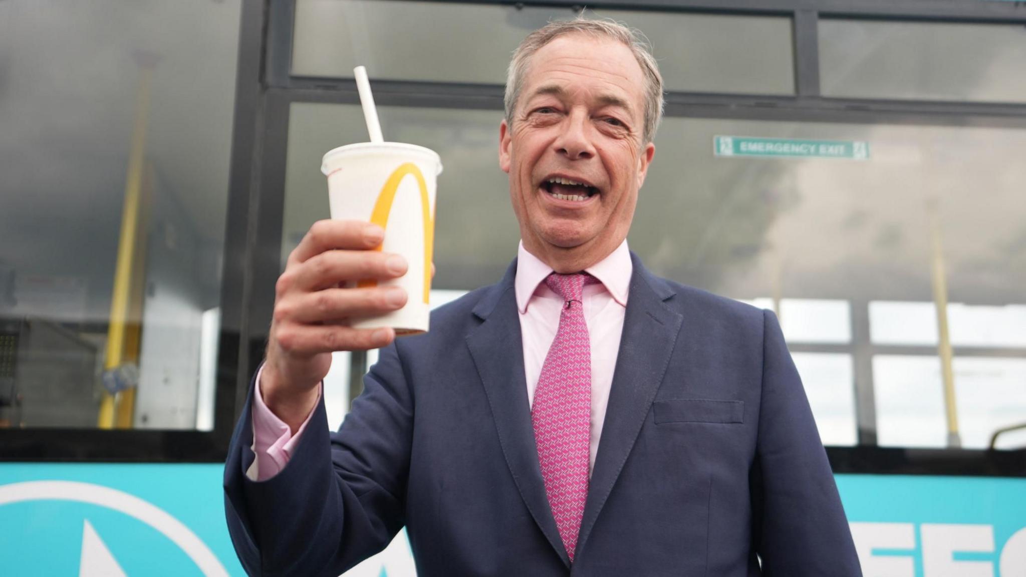 Nigel Farage holding a McDonalds milkshake in his right hand