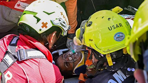 An international rescue team assists Hernan Gil, a survivor of Venezuela's twin earthquakes, in Catia La Mar, La Guaira State, Venezuela on July 2, 2026, eight days after the quake. Hernan Gil, a 43-year-old security guard, had been buried in the booth of the seven-story building where he worked in Catia La Mar, a coastal area in the state of La Guaira devastated by the disaster.