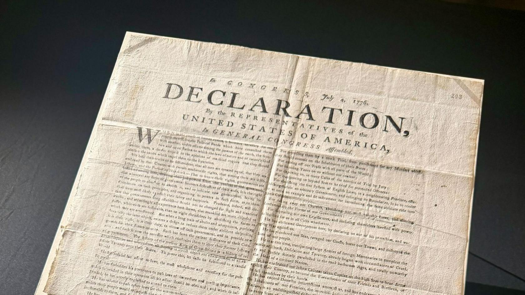 A copy of the US Declaration of Independence. The word "declaration" can be seen in capital letters on the document, which has various folds and creases.